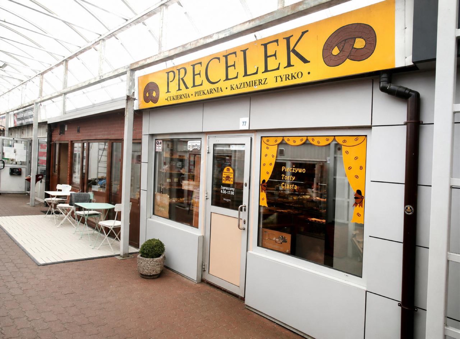 Witryna sklepu Precelek na ryneczku — żółty szyld „Precelek — Cukiernia Piekarnia, Kazimierz Tyrko”.